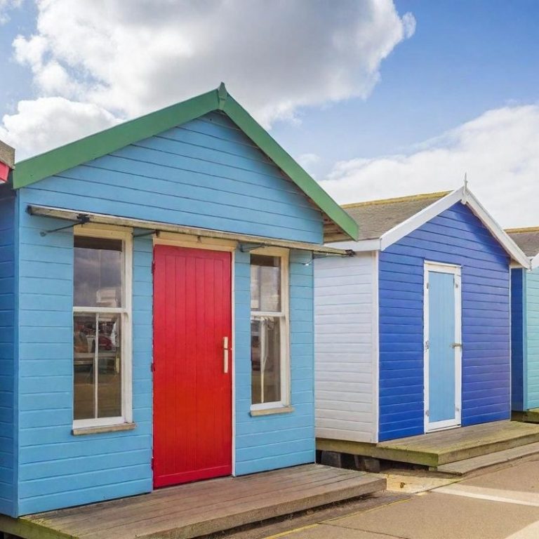 Lighthouse behind red-brick buildings under cloudy skies.